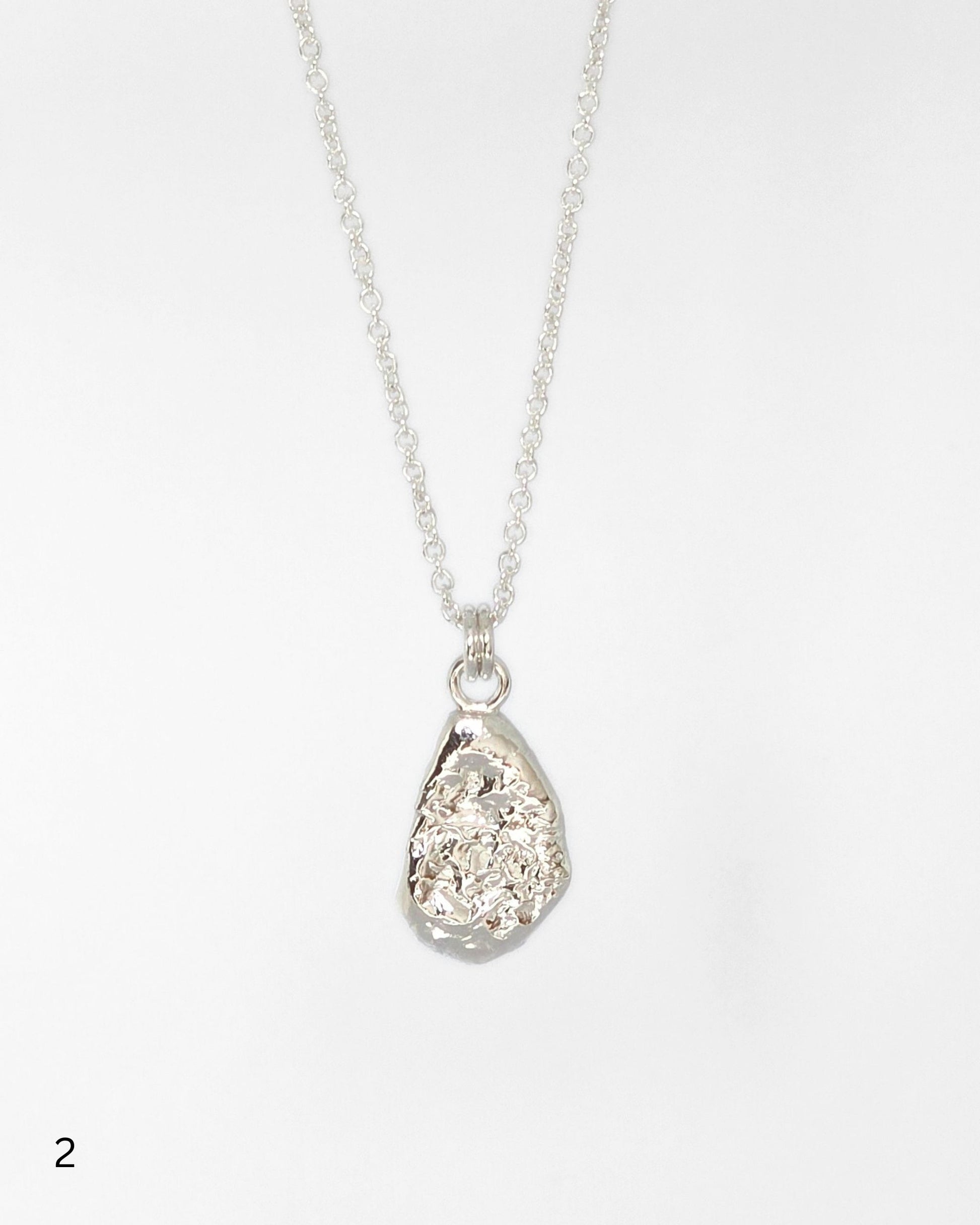 Sterling silver necklace with a teardrop-shaped textured molten pendant on a white background