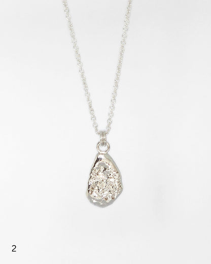 Sterling silver necklace with a teardrop-shaped textured molten pendant on a white background