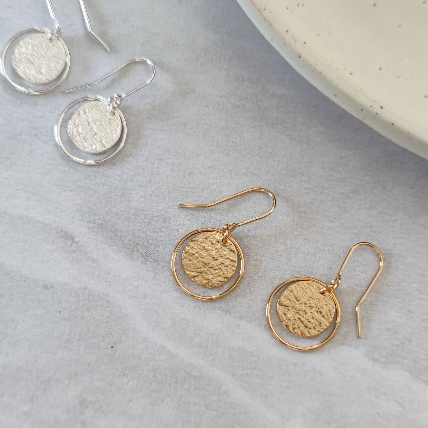 gold and silver roundabout earrings by aurelium on marble background