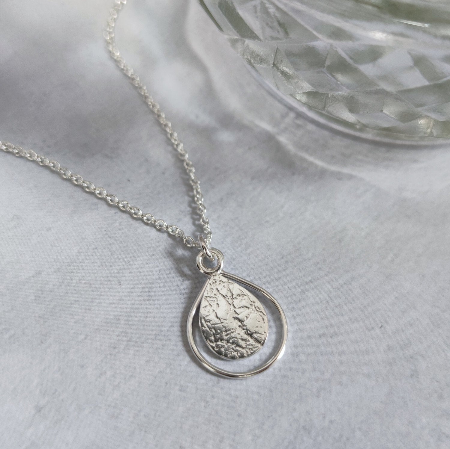 sterling silver dewdrop necklace by aurelium lying on marble surface