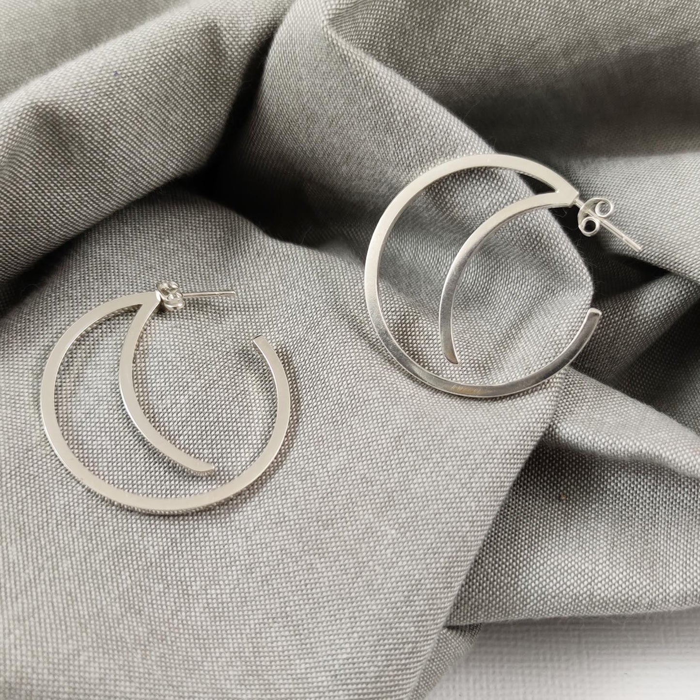 handmade sterling silver luna earrings lying on grey fabric