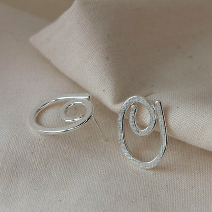 handmade sterling silver scribble earrings lying on cream fabric